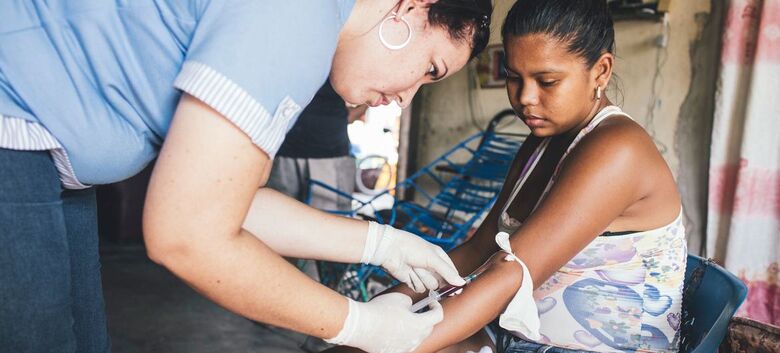 Um profissional de saúde coleta amostras de sangue de uma mulher que já havia contraído dengue - Crédito: Opas/Joshua E. Cogan