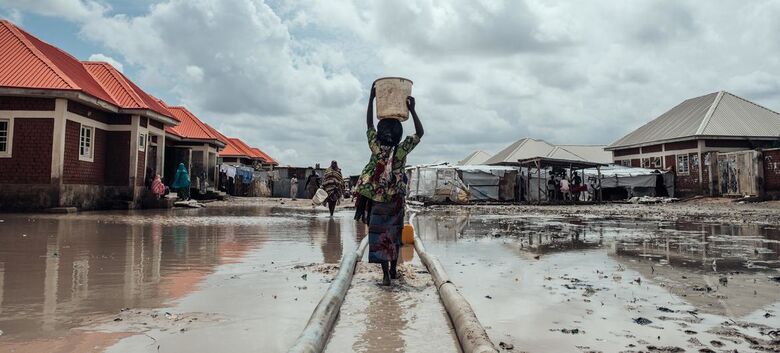 Milhões estão deslocados em toda a Nigéria devido a conflitos, impactos das alterações climáticas e catástrofes naturais. Nesta foto de arquivo, uma menina leva água para seu abrigo em um campo de deslocados internos no nordeste do país - Crédito:  Unicef/KC Nwakalor