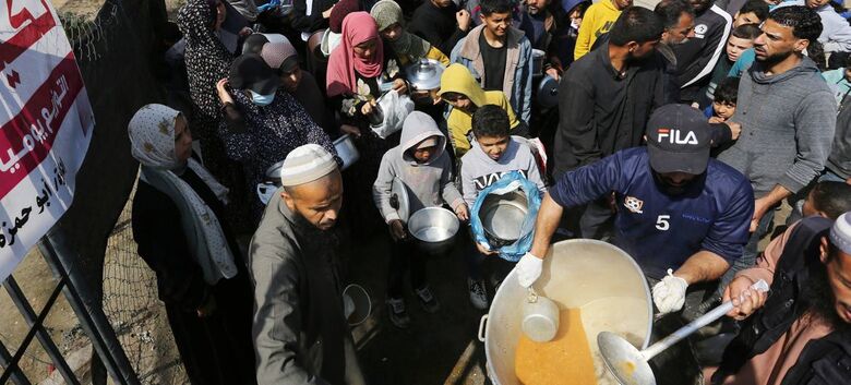  Pessoas aguardam em fila por comida em Gaza - Crédito:  Unrwa