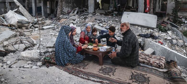 Uma família em Gaza faz uma refeição entre os escombros de sua casa - Crédito:  WFP/Ali Jadallah
