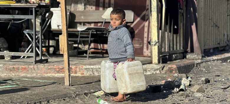Menino carrega latas de água na Faixa de Gaza - Crédito:  Unrwa