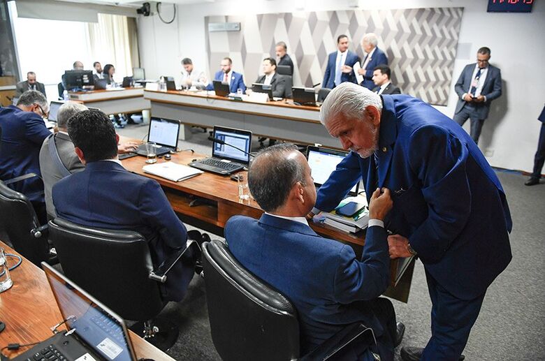  Os líderes do governo, Jaques Wagner, e da oposição, Rogério Marinho (de costas), conversam na última reunião da CCJ; sem regime de urgência, DPVAT volta à pauta da comissão   - Crédito: Roque de Sá/Agência Senado