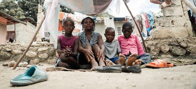 Uma mãe senta-se com seus filhos em um acampamento improvisado em Léogâne, nos arredores da capital haitiana, Porto Príncipe - Crédito:  Unicef/Maxime Le Lijour