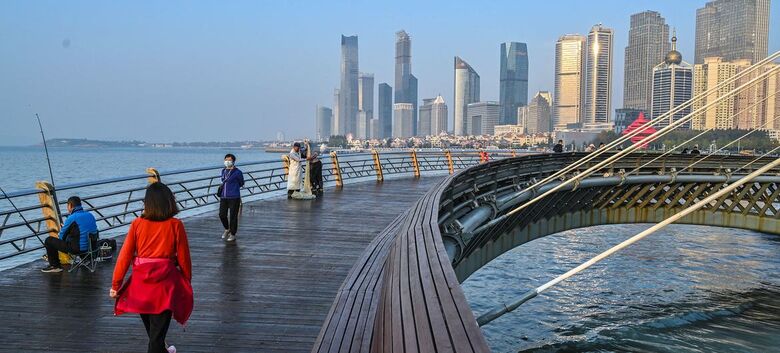 Pessoas caminham em uma ponte em um distrito de "energia inteligente e de baixo carbono" de Qingdao, na China - Crédito:  ADB/Deng Jia 